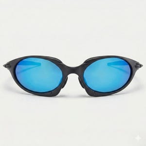 Puede incluir: Gafas de sol negras con montura ovalada y lentes azul brillante. Las gafas de sol tienen un dise&ntilde;o elegante y moderno, adecuado para actividades al aire libre. Las lentes reflejan la luz.