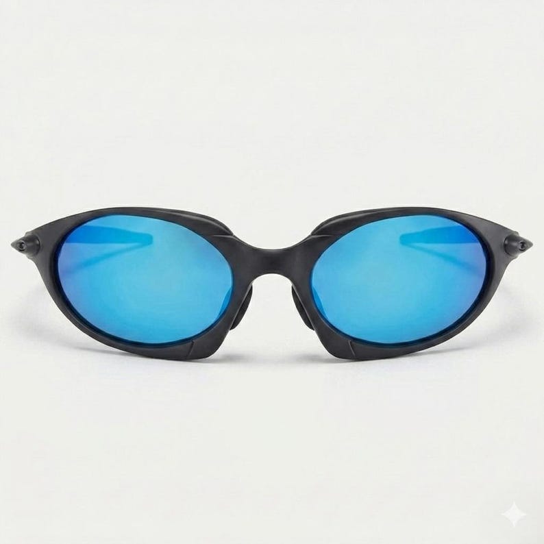 Puede incluir: Gafas de sol negras con montura ovalada y lentes azul brillante. Las gafas de sol tienen un dise&ntilde;o elegante y moderno, adecuado para actividades al aire libre. Las lentes reflejan la luz.