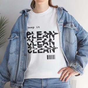 Peut inclure: T-shirt blanc avec l'inscription "keep it CLEAN" en noir, avec un effet ondulé et déformé. Le t-shirt est porté avec une veste en jean bleue et un jean bleu. Un code-barres est en bas du motif.