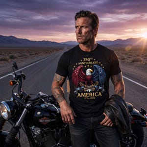 Puede incluir: Camiseta negra con un dise&ntilde;o patri&oacute;tico que celebra el 250 aniversario de Am&eacute;rica. El gr&aacute;fico presenta un &aacute;guila calva con alas rojas y azules, el texto "AMERICA 1776-2026" y estrellas. Tambi&eacute;n se ve una motocicleta negra.