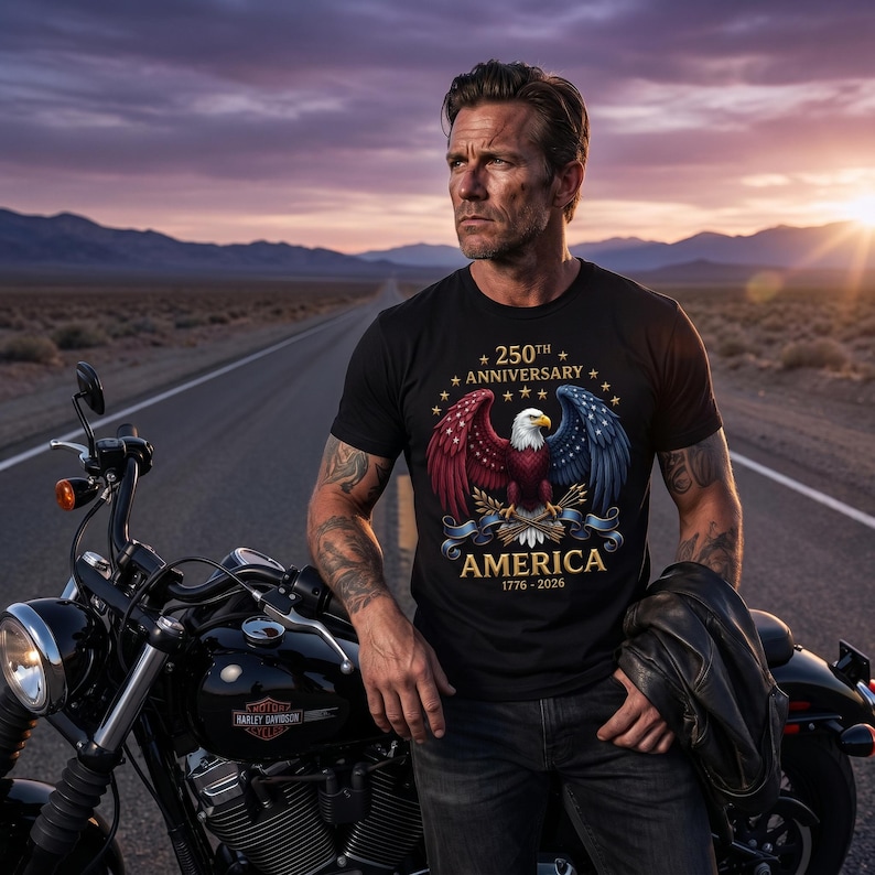 Puede incluir: Camiseta negra con un dise&ntilde;o patri&oacute;tico que celebra el 250 aniversario de Am&eacute;rica. El gr&aacute;fico presenta un &aacute;guila calva con alas rojas y azules, el texto "AMERICA 1776-2026" y estrellas. Tambi&eacute;n se ve una motocicleta negra.