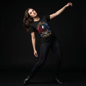 Puede incluir: Camiseta negra con un dise&ntilde;o patri&oacute;tico de &aacute;guila en rojo, blanco y azul, y el texto "250th Anniversary America 1776-2026". La persona lleva vaqueros negros.