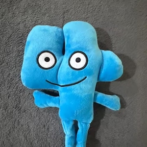 May include: A plush toy in the shape of the number four, in bright blue. The toy has large, round eyes with black pupils and white surrounds, a smiling mouth, and small arms and legs. The plush is soft and fluffy.