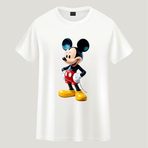 May include: A white short-sleeved t-shirt featuring a centered graphic of Mickey Mouse. The character is depicted with his signature black ears, red shorts with two white buttons, white gloves, and large yellow shoes, standing in a classic pose.