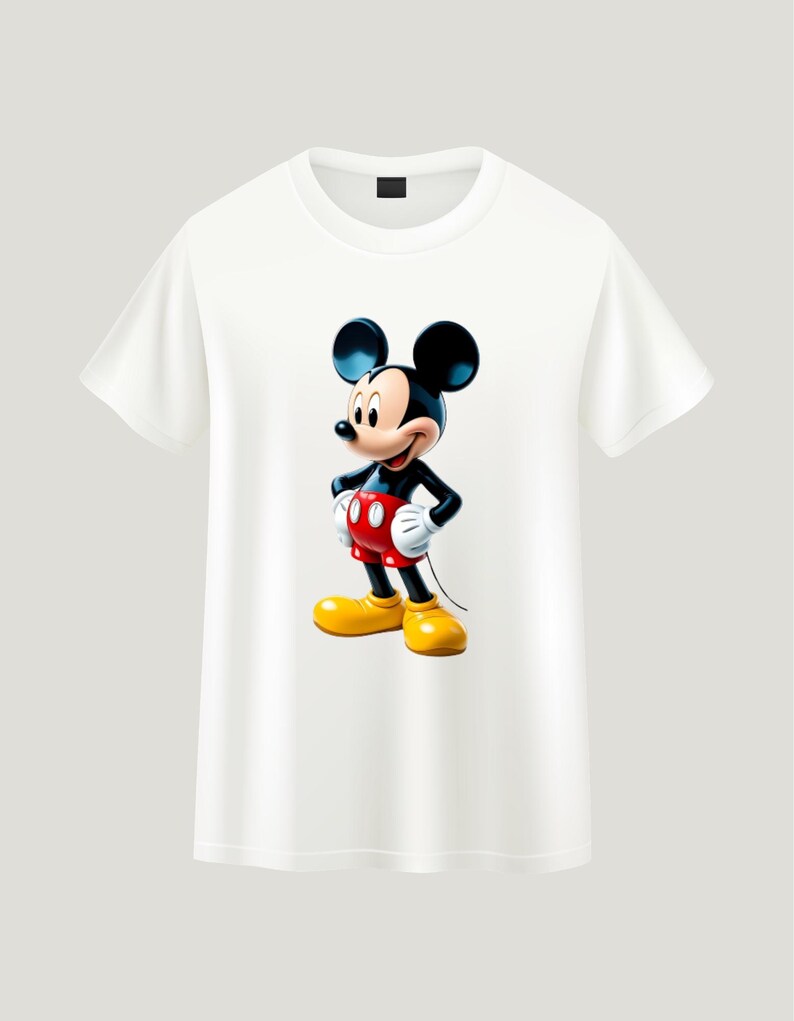 May include: A white short-sleeved t-shirt featuring a centered graphic of Mickey Mouse. The character is depicted with his signature black ears, red shorts with two white buttons, white gloves, and large yellow shoes, standing in a classic pose.