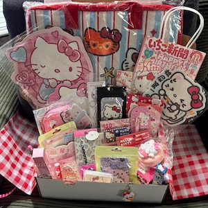 Puede incluir: Una colección de artículos de Hello Kitty que incluye una bolsa de tela a rayas, una bolsa de regalo de papel con texto en japonés, varios artículos de papelería, pequeños accesorios y pegatinas empaquetadas, todos con el icónico personaje.