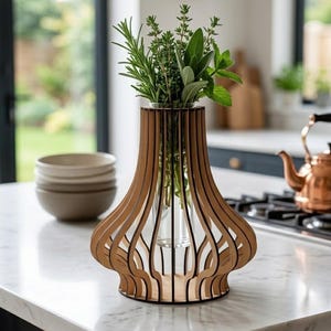 Peut inclure: Un vase en bois composé d'une série de lattes verticales incurvées formant une structure en cage autour d'un cylindre central en verre transparent. Le vase contient un assortiment d'herbes fraîches vertes, dont du romarin, du thym et de la sauge.