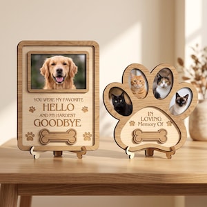 May include: Two light-colored wooden pet memorial frames. The rectangular frame features a golden retriever photo and the text "YOU WERE MY FAVORITE HELLO AND MY HARDEST GOODBYE" with a bone icon. The paw-shaped frame holds three cat photos.