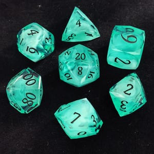 May include: A set of seven translucent mint green polyhedral dice with swirling white inclusions and black engraved numbers. The collection includes a d20, d12, d10, d8, d6, d4, and a percentile die, all featuring sharp edges and clear, legible numerals.