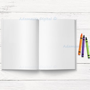 May include: An open, blank notebook with white pages, next to three crayons in orange, purple, and green. The notebook is on a white wooden surface, ideal for sketching or writing.
