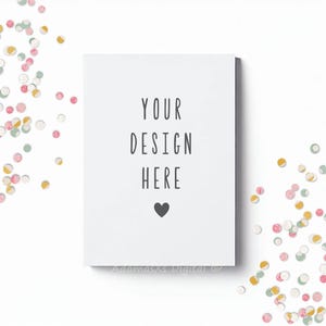 May include: A white card with the text "YOUR DESIGN HERE" and a black heart. Colorful confetti in pink, yellow, and green surrounds the card, creating a festive backdrop. The card is centered.