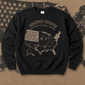May include: Black sweatshirt with a graphic of the United States map and the text "UNITED STATES WITHOUT ILLEGAL ALIENS" in a tan color. The map includes the American flag design. The sweatshirt is a crew neck style.