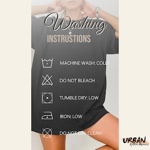 Op de afbeelding: Een zwart t-shirt met witte wasinstructies. De instructies omvatten machinewas koud, niet bleken, drogen in de droger op lage temperatuur, strijken op lage temperatuur en niet chemisch reinigen. Het Urban Cotton Apparel-logo staat rechtsonder.