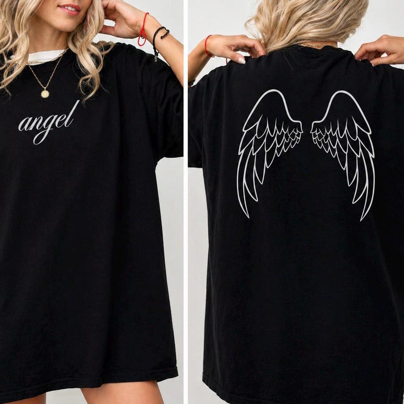 Op de afbeelding: Zwart oversized T-shirt met het woord "angel" in cursiefschrift op de voorkant. De achterkant van het shirt heeft een witte afbeelding van engelen vleugels. Het shirt heeft een ronde hals en korte mouwen.