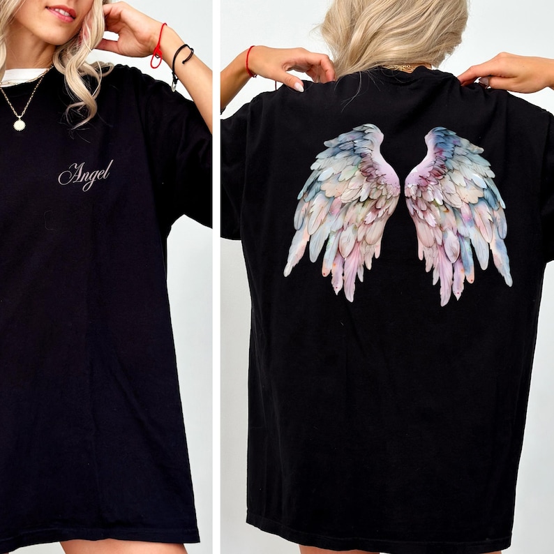 May include: Black t-shirt with the word "Angel" in cursive script on the front. The back of the shirt features a colorful, detailed illustration of angel wings in shades of pink, blue, and cream.