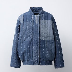 Könnte beinhalten: Eine blaue Patchwork-Bomberjacke aus verschiedenen Denim-Stofftönen. Die Jacke verfügt über einen Stehkragen, lange Ärmel, einen Frontreißverschluss sowie gerippte Bündchen und einen gerippten Saum. Weiße vertikale Steppstiche verzieren die Oberfläche.