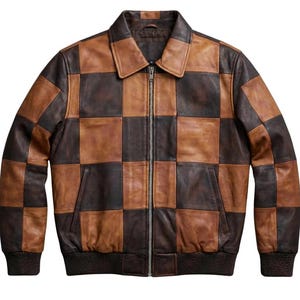 Puede incluir: Chaqueta de cuero marrón y marrón oscuro con un diseño de tablero de ajedrez. La chaqueta tiene cierre de cremallera, cuello y dos bolsillos delanteros. Los puños y el dobladillo son acanalados.