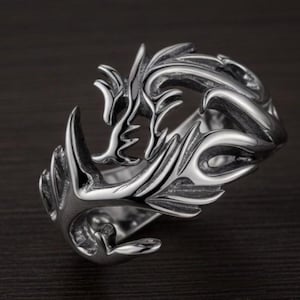 Peut inclure: Une bague argentée avec un design complexe et fluide. La bague présente une série de formes et de courbes organiques stylisées, créant une apparence dynamique et texturée. Le design est symétrique et s'enroule autour de l'anneau, lui donnant une qualité sculpturale audacieuse.