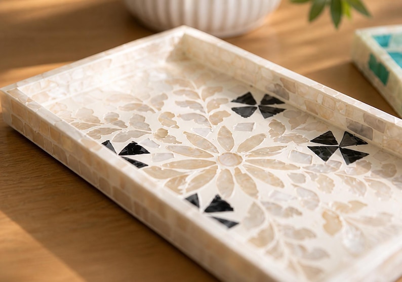 May include: Rectangular decorative tray with a mosaic floral design. The tray features a cream-colored background with a flower and leaf pattern in beige and black. The edges are also cream-colored and tiled.