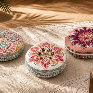 May include: Three round floor cushions featuring intricate mandala-style patterns in vibrant colors including pink, teal, yellow, and red. Each cushion has a thick, cylindrical shape with detailed geometric borders along the side panels.
