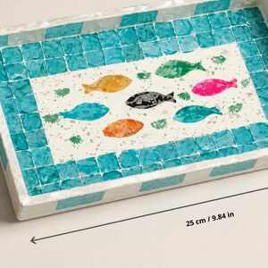 May include: Rectangular decorative tray with a mosaic tile border and a central design of colorful fish. The tray measures 9.84 inches long and 5.90 inches wide. The fish are in shades of yellow, green, pink, black, blue, and orange.