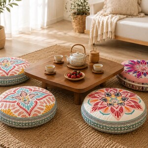 May include: Four round floor cushions featuring intricate mandala-style patterns in vibrant shades of pink, teal, yellow, and orange. Each cushion has a thick, cylindrical profile with a detailed geometric border along the side edges.