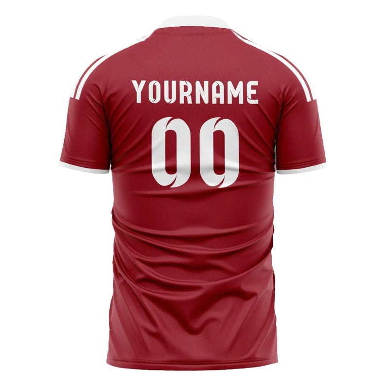 Puede incluir: Camiseta deportiva granate con detalles blancos. La parte trasera presenta el texto "YOURNAME" sobre el n&uacute;mero "00" en blanco. La camiseta tiene cuello blanco y rayas blancas en los hombros.