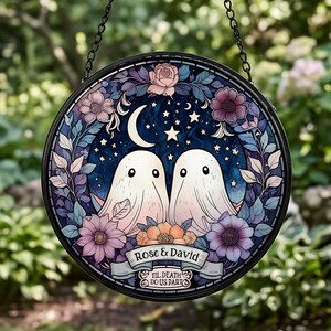 May include: A circular stained glass suncatcher featuring two white ghosts under a crescent moon and stars, surrounded by a floral wreath in shades of purple and pink. A banner displays the text Rose & David and Til Death Do Us Part.