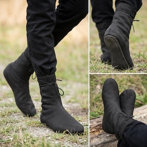May include: A pair of black leather ankle boots featuring a side-lacing design with thin black laces, a rounded toe, and a flat, textured sole. The boots extend above the ankle and are secured with a tie closure at the top of the side panel.