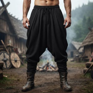 May include: Black drop-crotch trousers featuring a high elastic waistband with a drawstring closure, deep pleated detailing at the hips, and fitted cuffs at the ankles, paired with brown leather boots that reach the mid-calf.