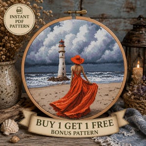 May include: A circular wooden embroidery hoop containing a cross-stitch pattern of a person in a long red dress and hat standing on a beach facing a lighthouse under a cloudy sky. A banner at the bottom reads BUY 1 GET 1 FREE BONUS PATTERN.