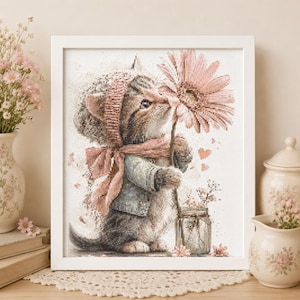May include: A framed cross-stitch embroidery depicting a tabby kitten wearing a pink bonnet and scarf, holding a large pink gerbera daisy. The kitten is dressed in a light blue jacket, standing beside a small glass jar with tiny flowers.