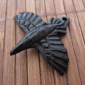 May include: Black raven pendant charm made of polymer clay. The raven is in flight with its wings spread out. The pendant is detailed with textured feathers.