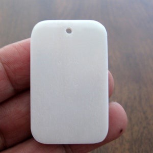 May include: A white rectangular shell pendant with a hole at the top for hanging.