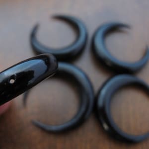 May include: Five black horn crescent moon shapes with a small hole in the center of each.