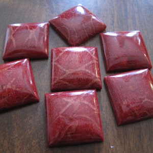 May include: Eight square red coral cabochons with a polished finish. The cabochons have a natural veined pattern.