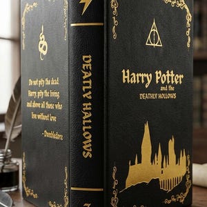 Op de afbeelding: Een zwart boek met gouden letters en details, getiteld "Harry Potter and the Deathly Hallows". De rug toont "Deathly Hallows" met een bliksemschicht. Een citaat van Dumbledore is ook aanwezig.