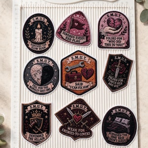 May include: A collection of nine decorative stickers with a vintage aesthetic. Each sticker features the letters "S.M.U.T." and various illustrations, including a candle, a broken heart, a bed, and text like "Ignored Every Red Flag."