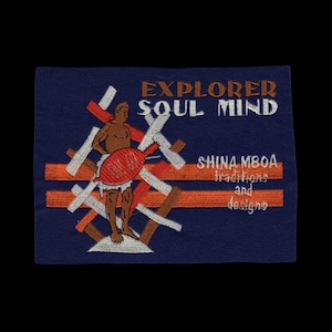 Peut inclure: Un écusson rectangulaire en tissu bleu marine avec une broderie indiquant EXPLORER SOUL MIND et SHINA MBOA traditions and designs. Le motif représente une silhouette brune tenant un objet ovale rouge sur des barres croisées blanches et orange.