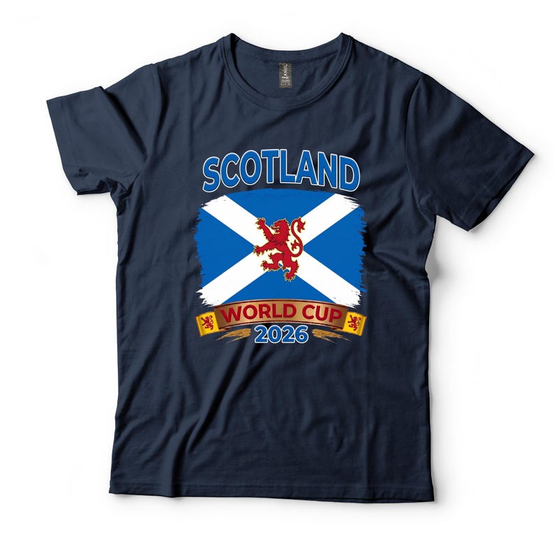May include: Navy blue t-shirt featuring the Scottish flag with a white X on a blue background and a red lion in the center. The text "SCOTLAND" is above the flag, and "WORLD CUP 2026" is below.