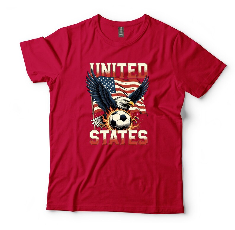 K&ouml;nnte beinhalten: Ein rotes Kurzarm-T-Shirt mit einer Grafik eines Wei&szlig;kopfseeadlers mit ausgebreiteten Fl&uuml;geln, einem Fu&szlig;ball und einer wehenden amerikanischen Flagge. Der Text UNITED STATES ist in einer fetten, hellen Schrift &uuml;ber und unter dem Motiv gedruckt.