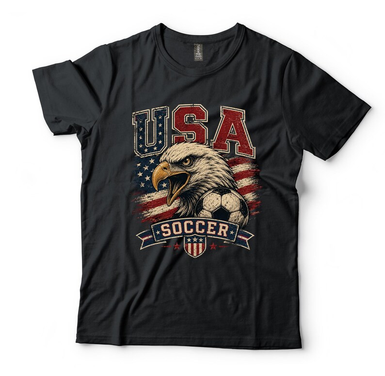 Puede incluir: Una camiseta negra de manga corta con un estampado gr&aacute;fico de un &aacute;guila calva, un bal&oacute;n de f&uacute;tbol y el texto USA SOCCER. El dise&ntilde;o incorpora colores rojo, blanco y azul con un patr&oacute;n de fondo de bandera estadounidense de estilo vintage.