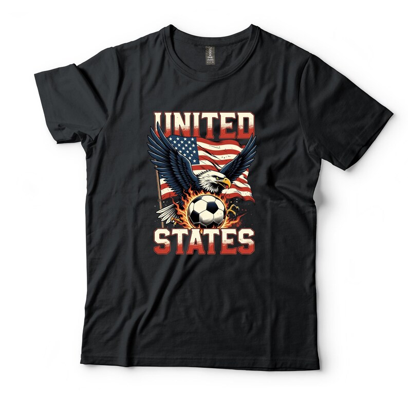 K&ouml;nnte beinhalten: Ein schwarzes Kurzarm-T-Shirt mit einem Grafikdruck eines Wei&szlig;kopfseeadlers mit ausgebreiteten Fl&uuml;geln &uuml;ber einem von Flammen umgebenen Fu&szlig;ball. Hinter dem Adler weht eine amerikanische Flagge. Der Text UNITED STATES ist in roten Buchstaben gedruckt.