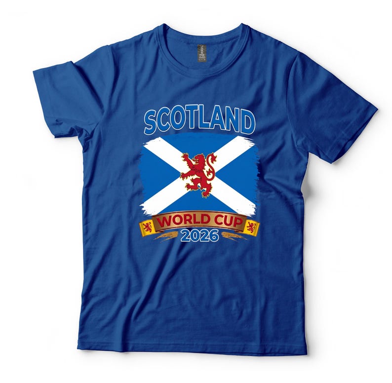 May include: Royal blue t-shirt featuring the Scotland flag with a white cross on a blue background and a red lion in the center. The text "SCOTLAND" is above the flag, and "WORLD CUP 2026" is below.