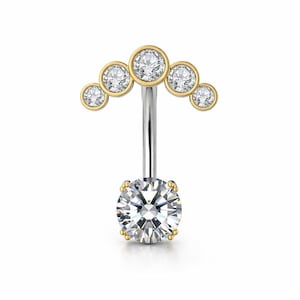 Könnte beinhalten: Ein Bauchnabelpiercing mit geschwungenem Design. Die Oberseite hat fünf klare, runde Edelsteine in goldfarbenen Fassungen. Die Unterseite hat einen größeren, runden Edelstein, der von einer goldfarbenen Fassung gehalten wird. Der gebogene Stab ist silberfarben.