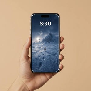 Op de afbeelding: Een smartphone toont een landschapsachtergrond met een pinguïn op een besneeuwd terrein met bergen. De tijd "8:30" wordt bovenaan weergegeven. De telefoon wordt in een hand gehouden tegen een neutrale achtergrond.