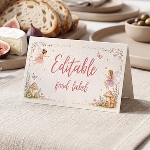 May include: A folded cream-colored card featuring the text Editable food label in pink script. The design includes illustrations of two fairies, butterflies, small flowers, and mushrooms arranged in a decorative border on the front of the card.