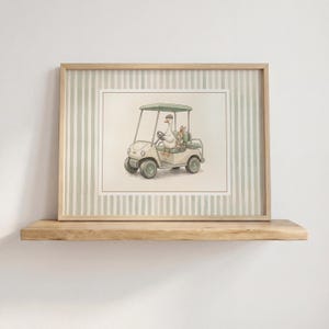 Può includere: Illustrazione ad acquerello di un'oca che guida un'auto da golf con un coniglio passeggero. Il carrello è beige con una capote e ruote verdi. L'opera d'arte è incorniciata in una cornice di legno chiaro con uno sfondo a righe verdi e bianche.