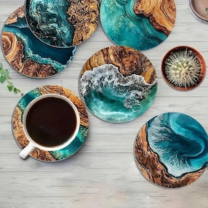 Puede incluir: Un conjunto de posavasos redondos con un diseño costero. Los posavasos presentan una mezcla de colores turquesa, marrón y blanco, que se asemejan a las olas del océano y las playas arenosas. Una taza de café se encuentra sobre un posavasos a juego.