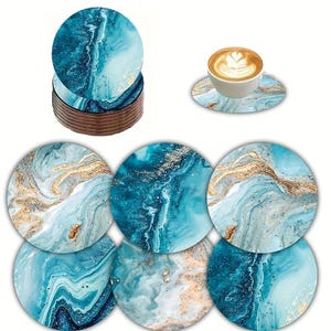 Pode incluir: Um conjunto de bases para copos redondas com um padrão de mármore em tons de azul-petróleo, azul e branco com detalhes em dourado. As bases são apresentadas empilhadas e individualmente, com uma chávena de café branca sobre uma delas.